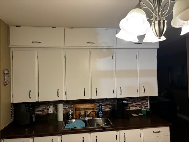 The same kitchen after refinishing: bright white cabinet doors with new hardware